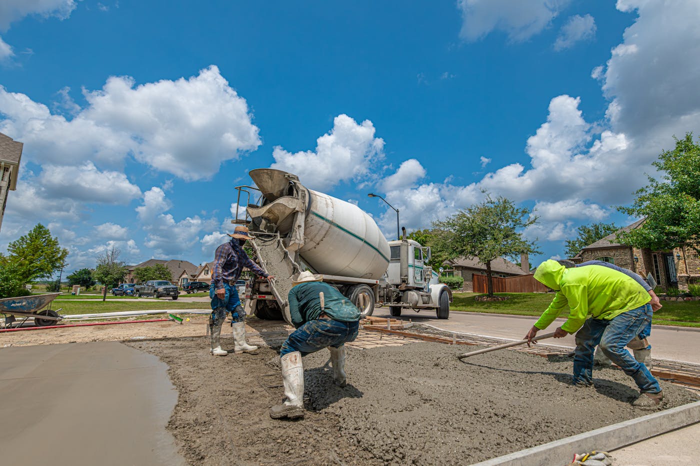 Workers pouring and finishing a concrete driveway